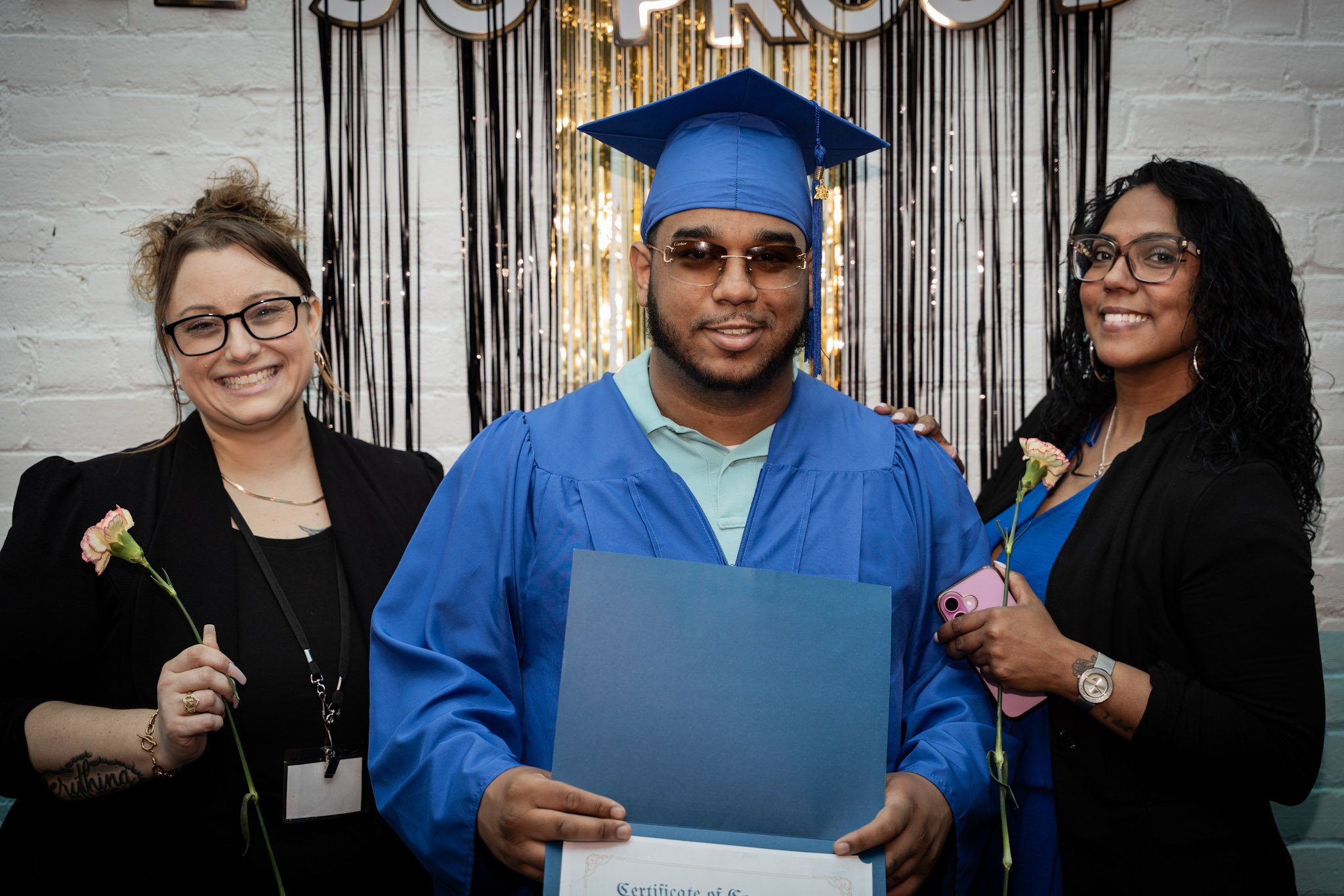 An ASCEND graduate holding his certificate with program leaders